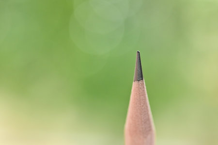 single sharp wooden pencil on green blur nature background with bokehの写真素材