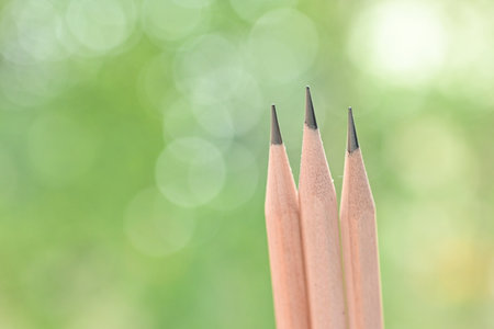 three sharp wooden pencil on green blur nature background with bokehの写真素材