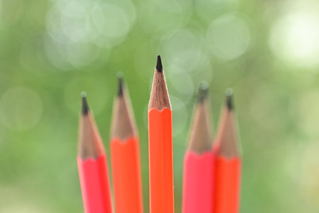 sharp pink and orange pencil on green blur nature background with bokeh