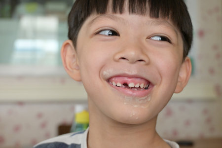 little messy boy with dirty face and lost a tooth, funny happy kid portraitの写真素材