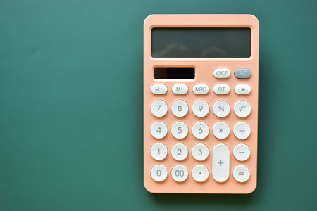 modern peach colour pastel calculator and white button on green background, business and finance accounting conceptの写真素材