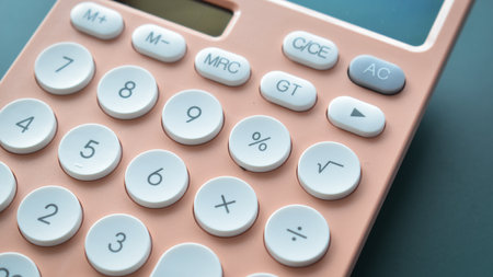 close up modern peach colour pastel calculator and white button on blue background, business and finance accounting conceptの写真素材
