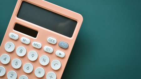 modern peach colour pastel calculator and white button on green background, business and finance accounting conceptの写真素材