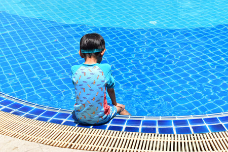 cute boy sit on the swimming pool, happy child