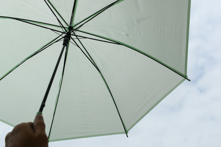 open green umbrella in rainy day with white cloud and blue skyの写真素材