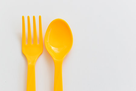 yellow spoon and fork isolated on white background, plastic cutlery for picnicの写真素材