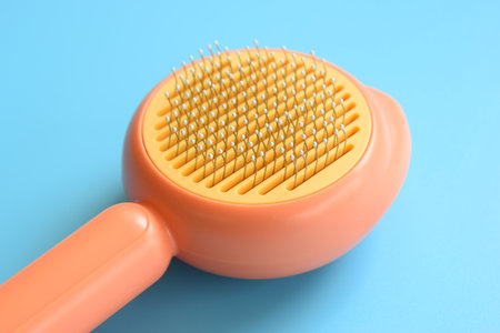 pastel orange comb on blue background, hair brush for petの写真素材