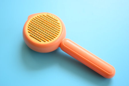 pastel orange comb on blue background, hair brush for petの写真素材