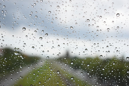 water drop on window with blue sky and green grassの写真素材