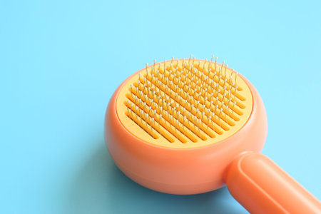 pastel orange comb on blue background, hair brush for petの写真素材