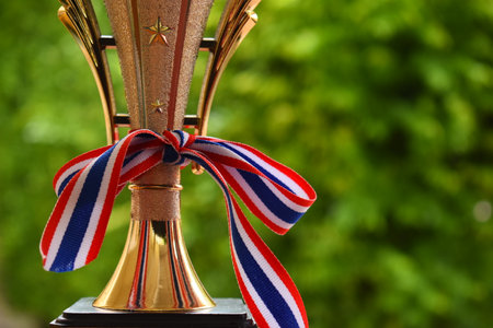beautiful golden trophy with thailand ribbon on green tree backgroundの写真素材