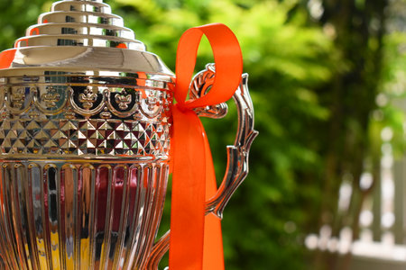 beautiful golden trophy with orange ribbon on green tree backgroundの写真素材