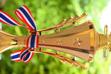 beautiful golden trophy with thailand ribbon on green tree backgroundの写真素材