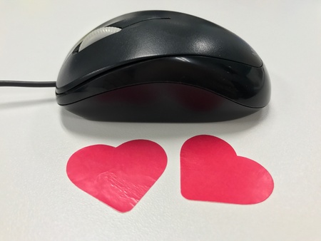 Black computer mouse with pink heart stickersの素材