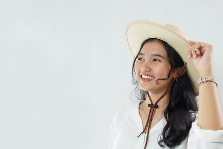 negative space of young Asian woman holding cowboy hat happily. woman in an all-white suit on a...