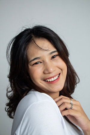 closeup of a young woman with a cheerful smiling pose showing her graceful shoulders, photogenic woman in a white suitの写真素材