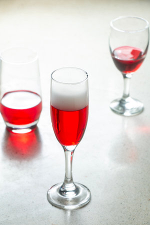 glass of Champagne Flute glass filled with red syrup and other types of glasses on terrazzo granite bar counter, red wine drink in glasses, drink partyの写真素材