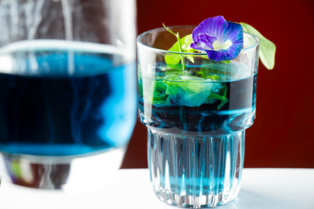 Purple flower tea or butterfly pea flower isolated with focus on a glass on an orange backgroundの写真素材