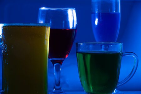 a collection of wine glasses next to half-full glasses. colorful cocktail glasses