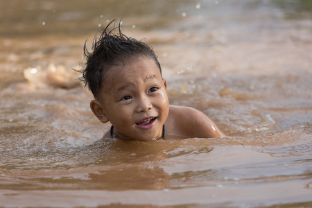 The boys played happily in the pond water.の写真素材