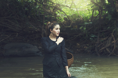 Beautiful girl standing in the stream and looking for someone.の写真素材