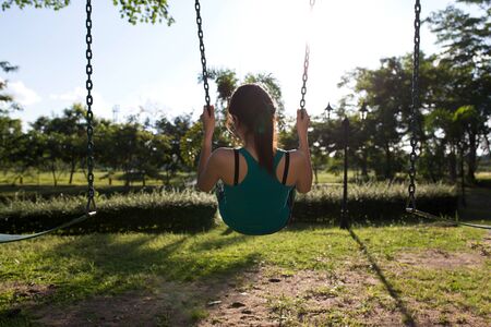 Back side woman sitting on Parks Play swingsの写真素材