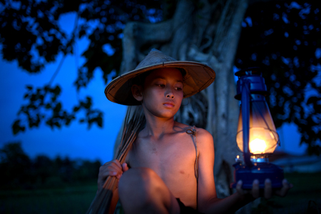 The hope of a boy with a lantern lighting while out fishing in the dark.の写真素材