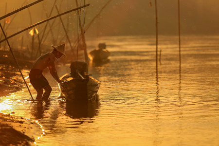 Silhouette fisherman with a boat at mekong river Pakse Champasak,Laos.の写真素材