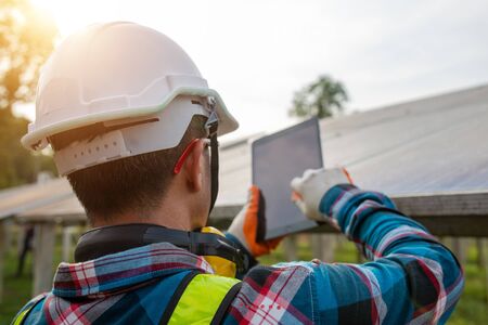 Engineer inspecting or repairing solar cells on a solar farm, checking the voltage with a tablet.の写真素材