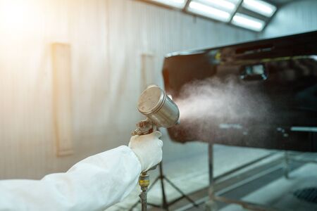 Spray gun paint car technician working in the color paint garage