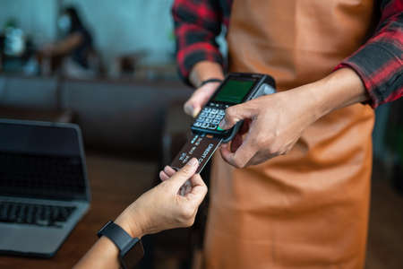 Payment by credit card via credit card swipe machine at cafeの写真素材