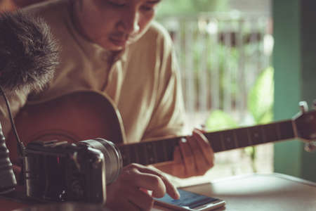 Young Asian man playing guitar relaxing in a cafe.の写真素材