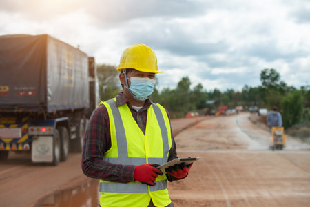 Foreman worker in uniform holding a tablet working in the road constructionの写真素材