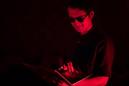 Portrait male uses a laptop hacker acting