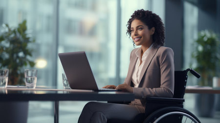 Businesswoman on the wheelchair working on the laptop in the modern white office in Americaの素材
