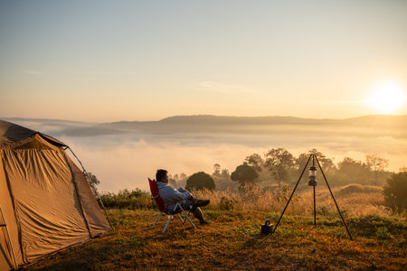 A young Campsite Plus man is sitting and admiring the misty mountain view.の写真素材