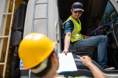 A man in a yellow vest is handing a piece of paper to another man in a yellow helmet