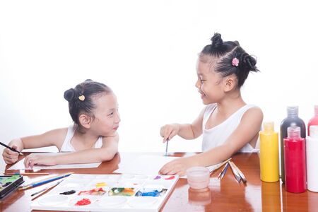 two sisters children black hair smile draw on the album. Isolated on white backgroundの写真素材