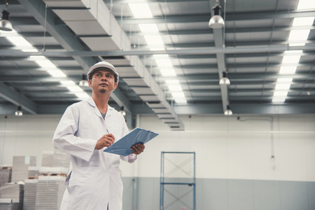 Young man white uniform checking stock at store factory