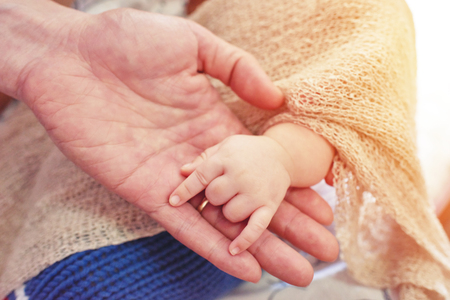 Baby makes a hand sign on the palm of his father.の写真素材