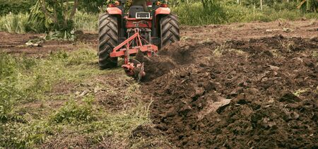 Agricultural workers with tractors, Tractor plowing fields preparing land for sowingの写真素材