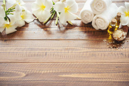Sea salt, towels, aroma oil in bottles and flowers on vintage wooden background. Selective focus.の写真素材