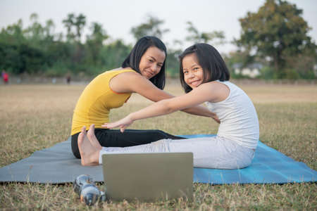 Mother and daughter doing yoga. woman and child training in the park. outdoor sports. healthy sport...