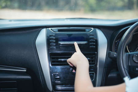 Hand of woman turning on car air condition system,Button on dashboard in car panel,Auto car air...