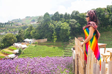 Beautiful Asian woman in colorful dress looking at view in flower garden park.の写真素材