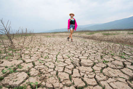 woman walking in dryland with drought ground texture. concept climate changed.の写真素材