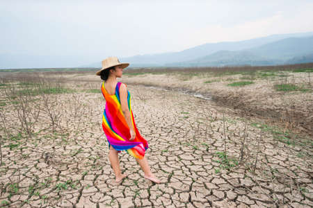 woman walking in dryland with drought ground texture. concept climate changed.の写真素材