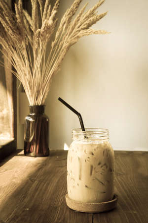 Ice coffee in a glass of jar on wooden table. Sepia and vintage tone.の写真素材