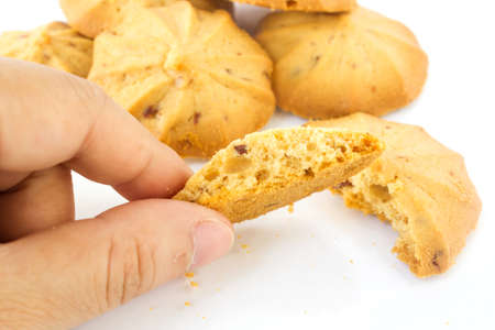 Closeup woman's hand picking butter cookies with rum raisin on white background.