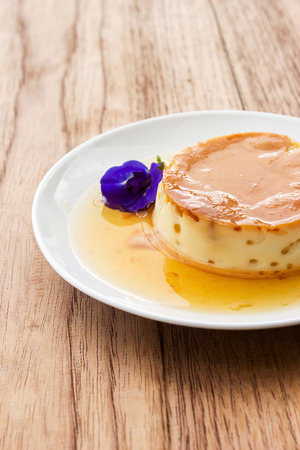 Homemade caramel custard pudding on white plate. Over wooden table.の写真素材